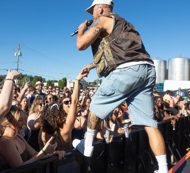 A performer in jean shorts reaches into the crowd at the Phillip's Backyard Summer Weekend Concert Series in Victoria, BC