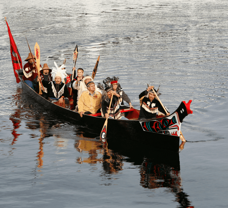 A group of Indigenous people paddling in a canoe in Victoria, BC