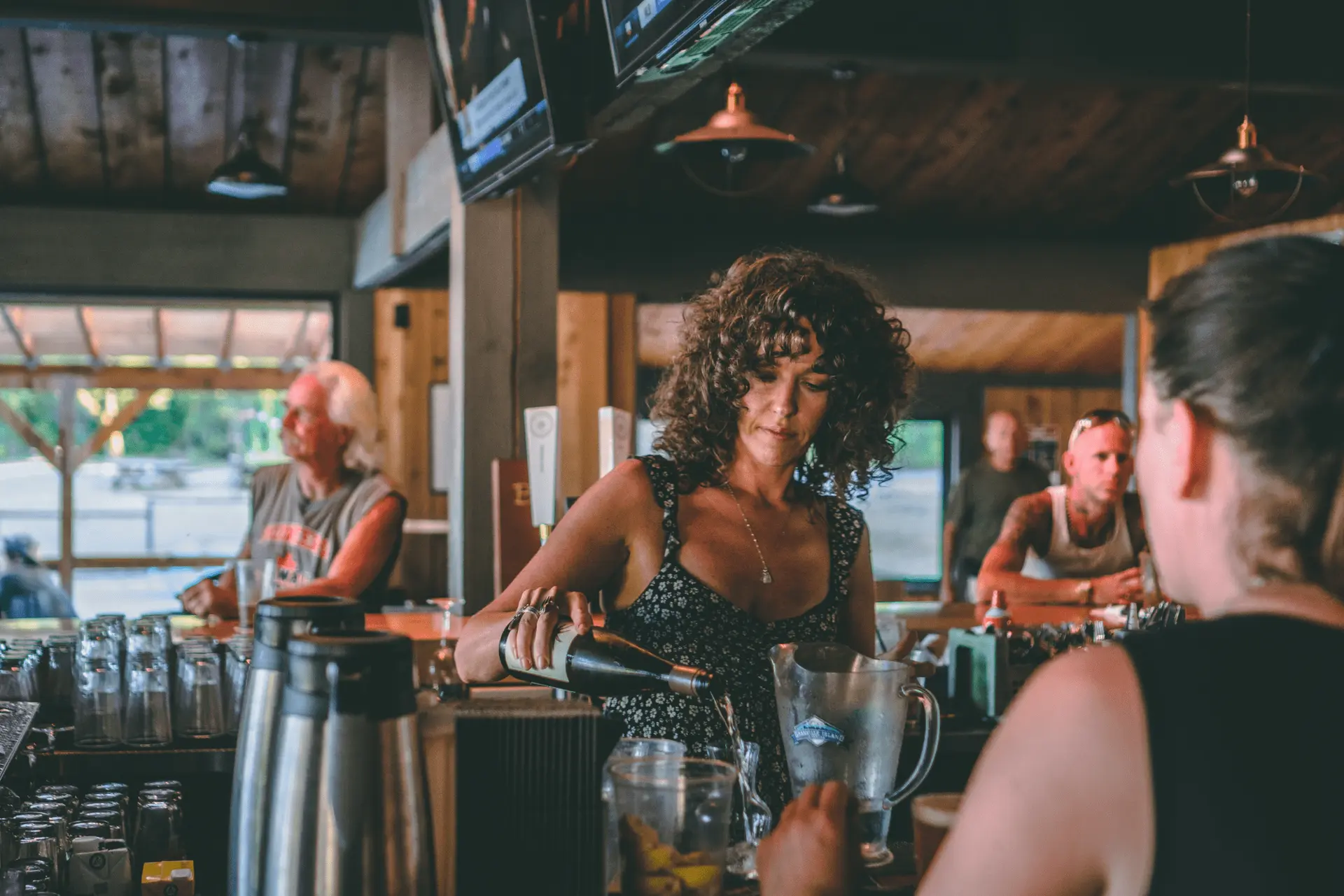 A woman pouring a drink at Port Browning Marina Pub & Cafe in VIctoria, BC