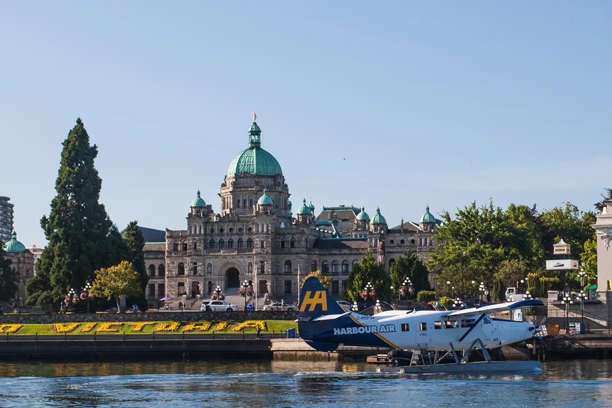 A Harbour Air seaplane takes off from the water in Victoria, BC in front of the BC Parliament Buildings