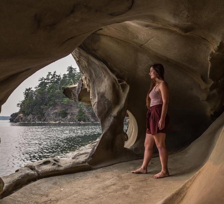 Woman in a cave overlooking a lake