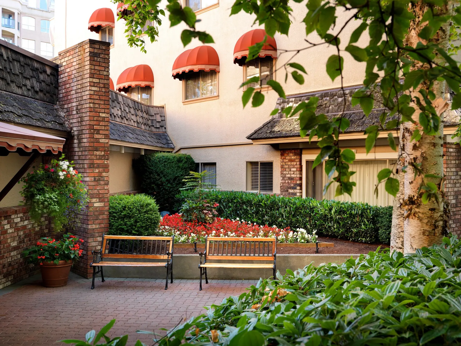 The back entrance of the Royal Scot Hotel in Victoria, BC showcasing a quaint garden and seating area