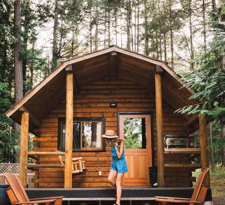 A woman coming out of a log cabin