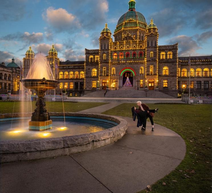 A couple walking in front of the legislature building in Victoria, BC