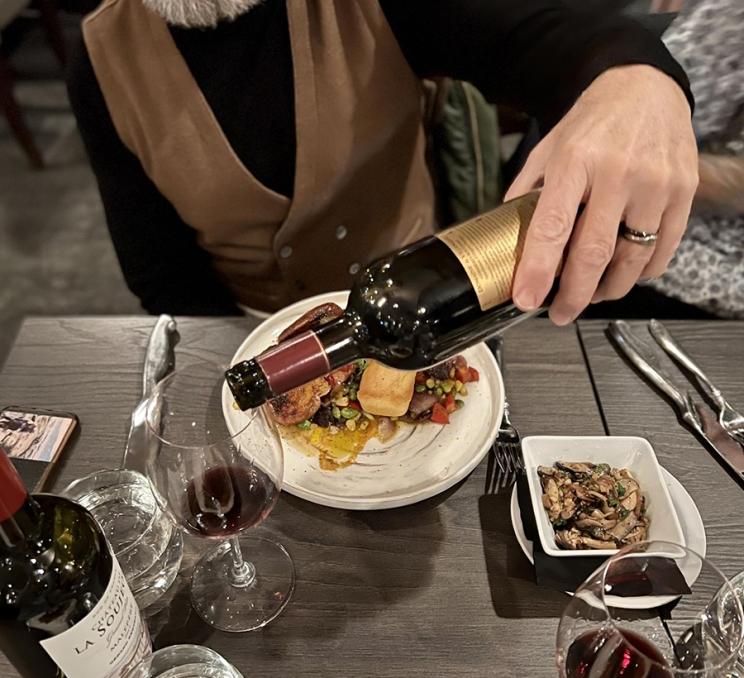 A couple enjoys dinner while a man pours wine at Vista 18 restaurant in Victoria, BC