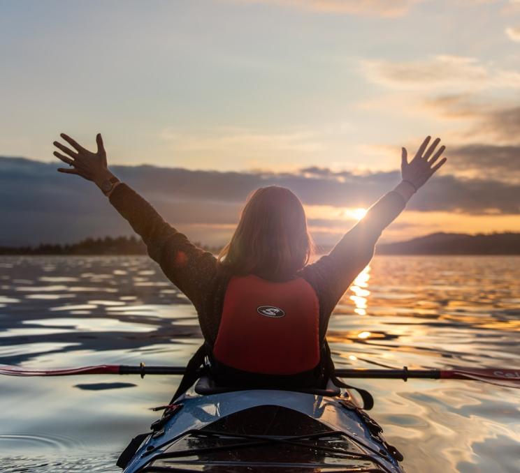 A woman takes in the sunset while kayaking along the Salish Sea in Victoria, BC
