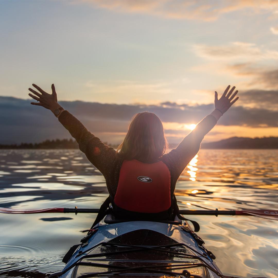 A woman takes in the sunset while kayaking along the Salish Sea in Victoria, BC
