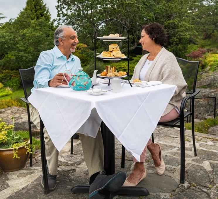 A couple enjoys afternoon tea on the patio at Abkhazi Garden in Victoria, BC