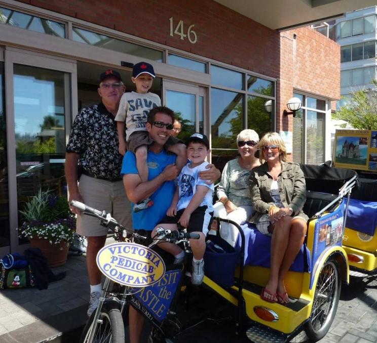 A guide and family pose for a photo with Victoria Pedicabs Company in Victoria, BC