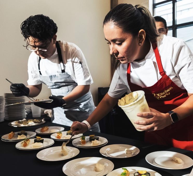 Chefs plating gourmet dishes during a culinary event.