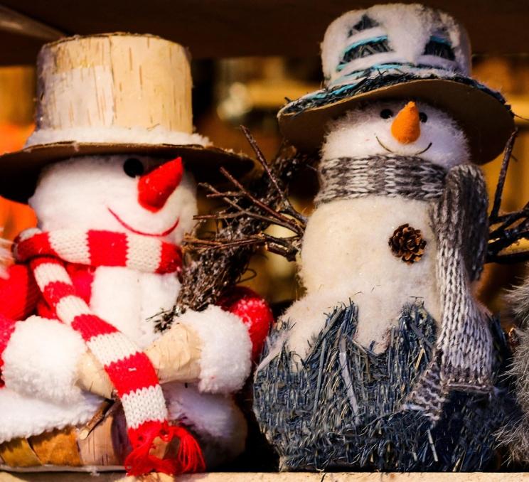 A pair of decorative stuffed snowmen in red and blue adorned with hats