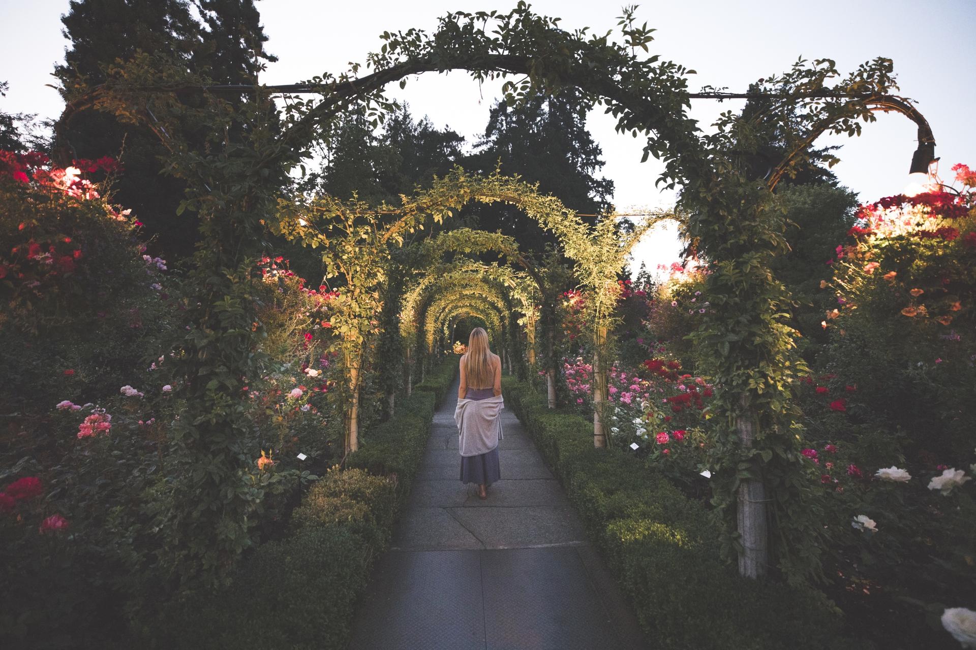 A woman walks beneath some arches at The Butchart Gardens in Victoria, BC