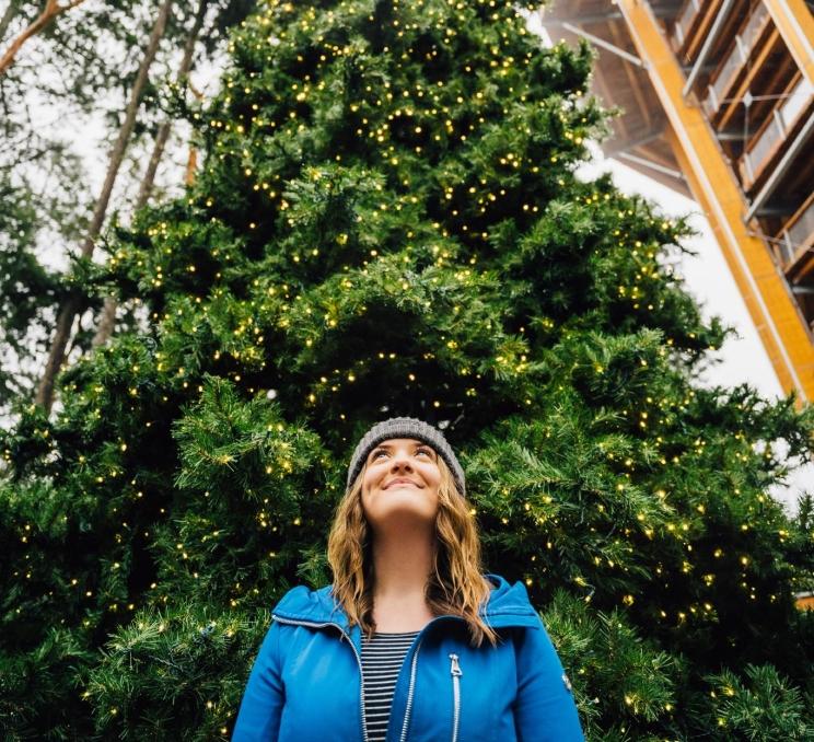 A woman stands below a pine tree at Malahat SkyWalk in Victoria, BC