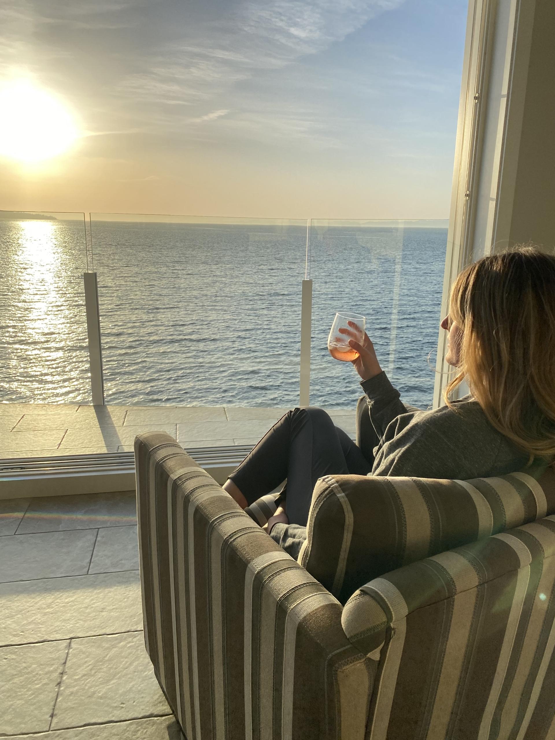 Women drinking a glass of wine looking out hotel window