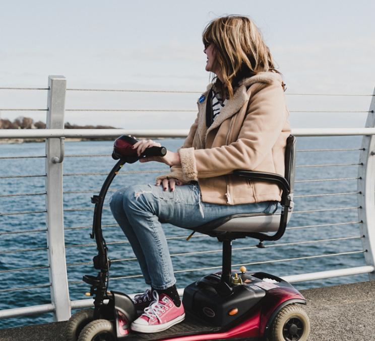 A woman on a mobility scooter rides along the Ogden Point Breakwater in Victoria, BC