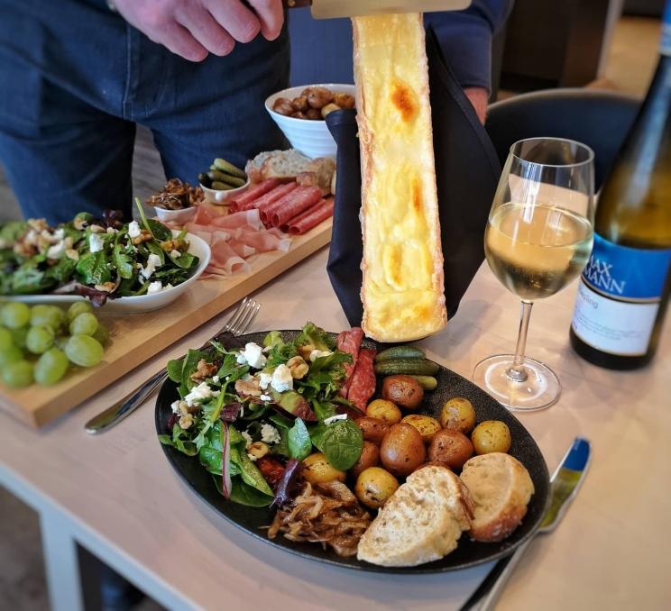 A raclette is about to spread over a meal at L'Apero Cheese & Wine Bar in Victoria, BC