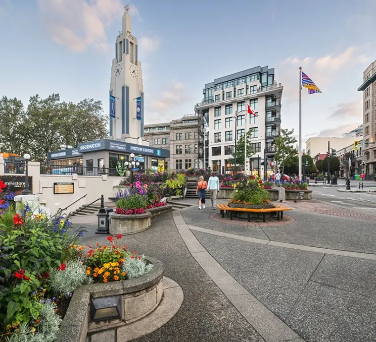 A couple walks past the Victoria Visitor Centre on the Upper Causeway of the Inner Harbour in Victoria, BC