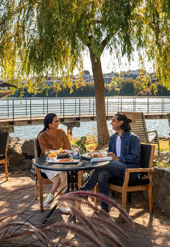 A couple dines on an oceanside patio at Glo Restaurant + Bar in Victoria, BC