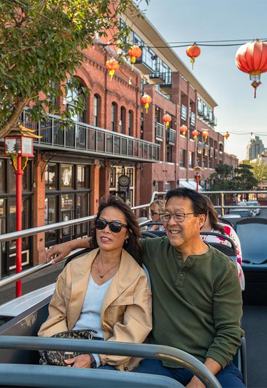 A couple enjoys a tour bus ride through Chinatown in Victoria, BC
