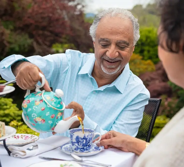 A man pours his wife tea at a gardenside teahouse, The Teahouse at Abkhazi Garden, in Victoria, BC