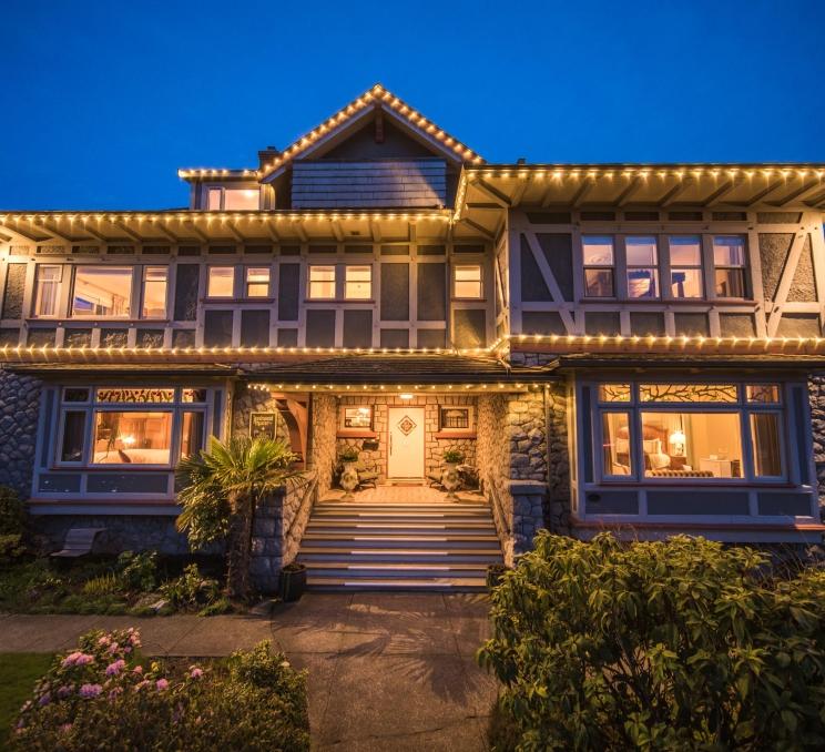 The exterior of Dashwood Manor Seaside Bed & Breakfast Inn illuminated by outdoor lighting at night in Victoria, BC