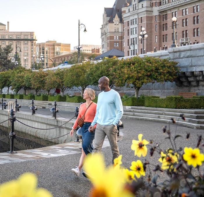 A couple walks along Victoria BC's Inner Harbour