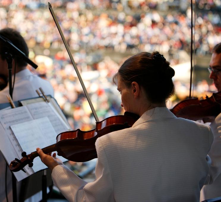 A violinist in a white shirt performs on a barge at Symphony Splash! a waterfront concert performed during Symphony in the Summer in Victoria, BC