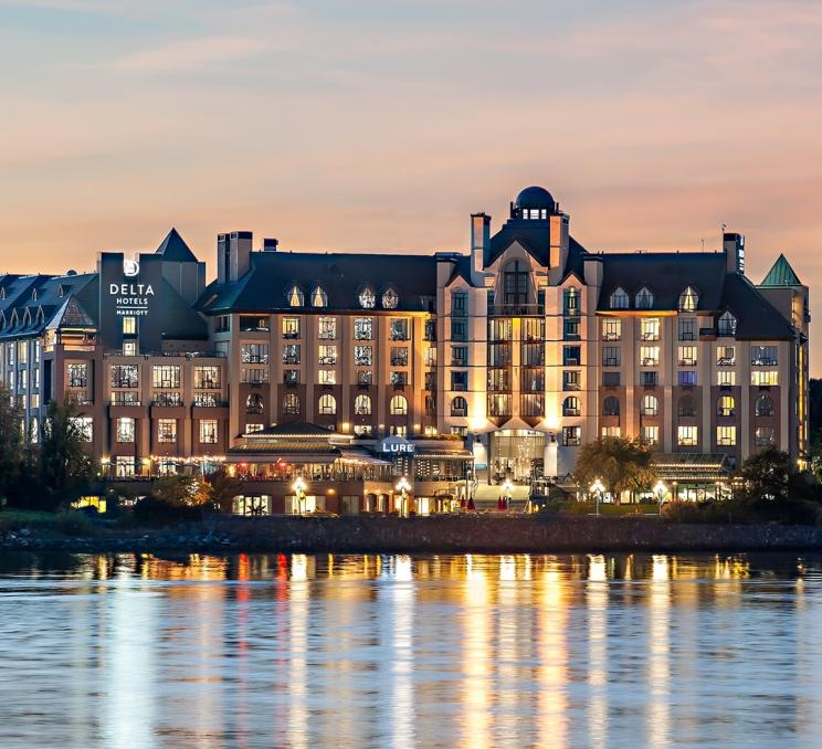 The Delta Hotels by Marriot Victoria Ocean Pointe Resort illuminated at sunset in Victoria, BC