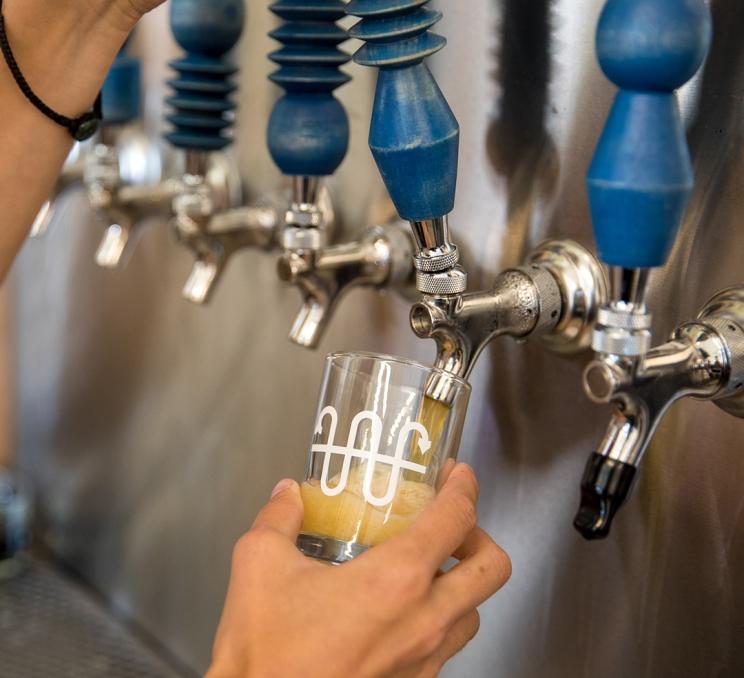A bartender pours a glass of beer from a tap at Whistle Buoy Brewing in Victoria, BC