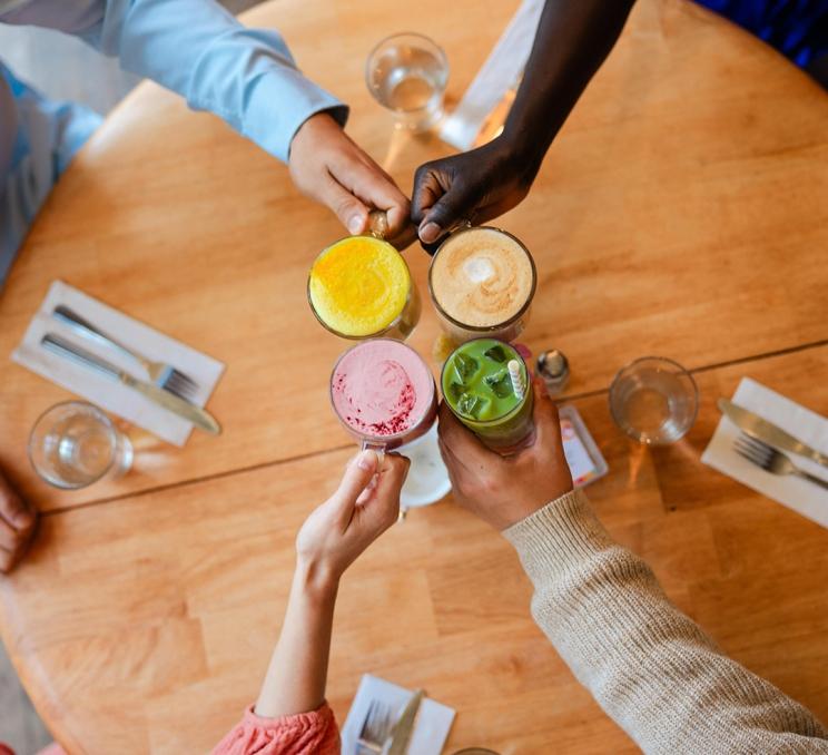 A group of friends cheers their lattes at Nourish Kitchen & Cafe in Victoria, BC