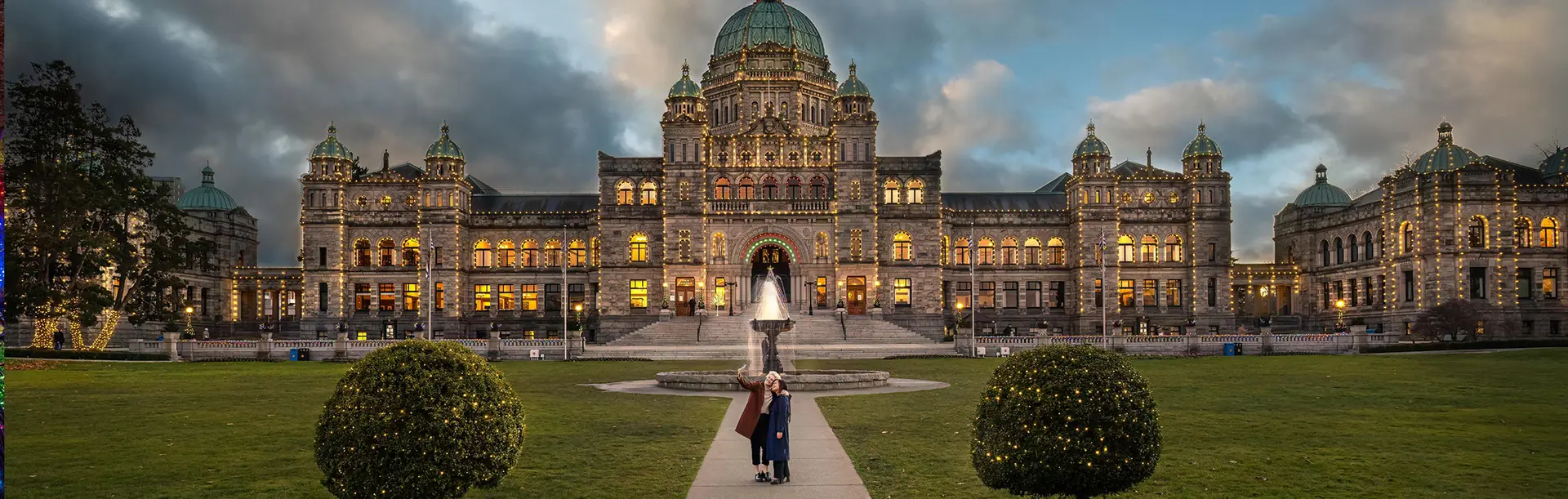 A couple takes a selfie outside of the BC Parliament Buildings during the holidays in Victoria, BC
