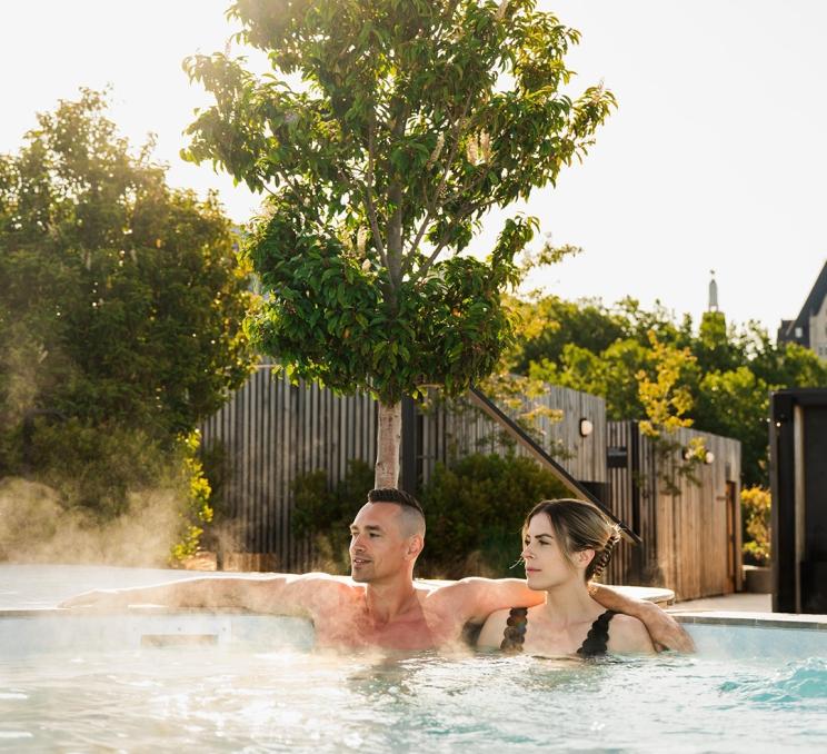 A couple soaks in a hot tub on the deck of HAVN Saunas on the Inner Harbour of Victoria, BC