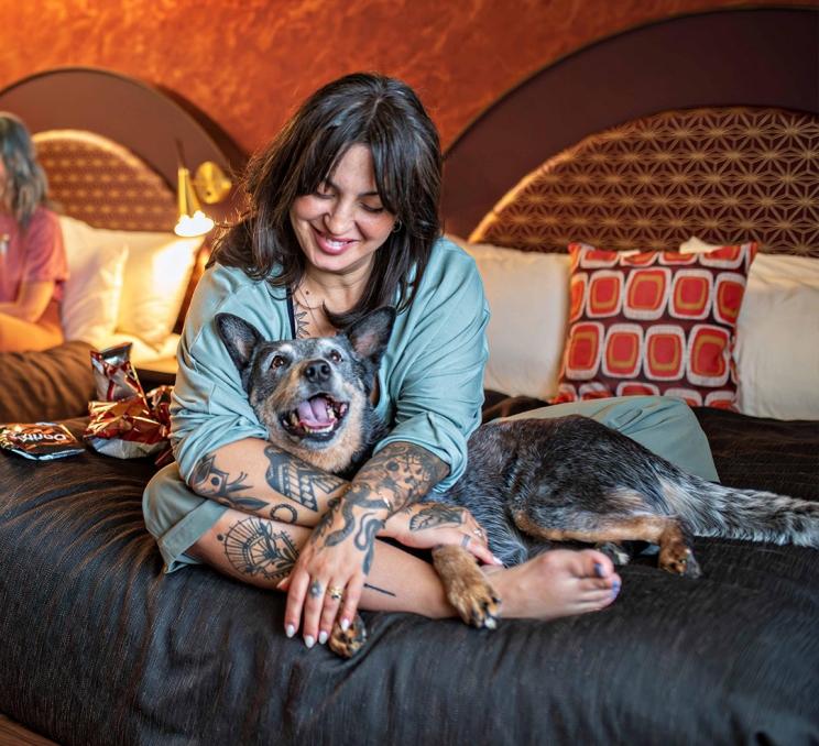 A woman lays on a bed with a Blue Heeler at Hotel Zed in Victoria, BC