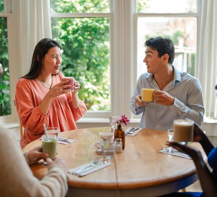 A couple enjoys lattes with their friends at Nourish Kitchen & Cafe in Victoria, BC