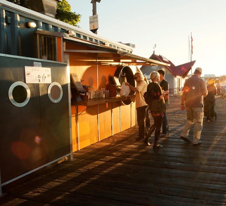A customer collects their order at Red Fish Blue Fish a fish and chips restaurant located on a dock along Victoria, BC's Inner Harbour