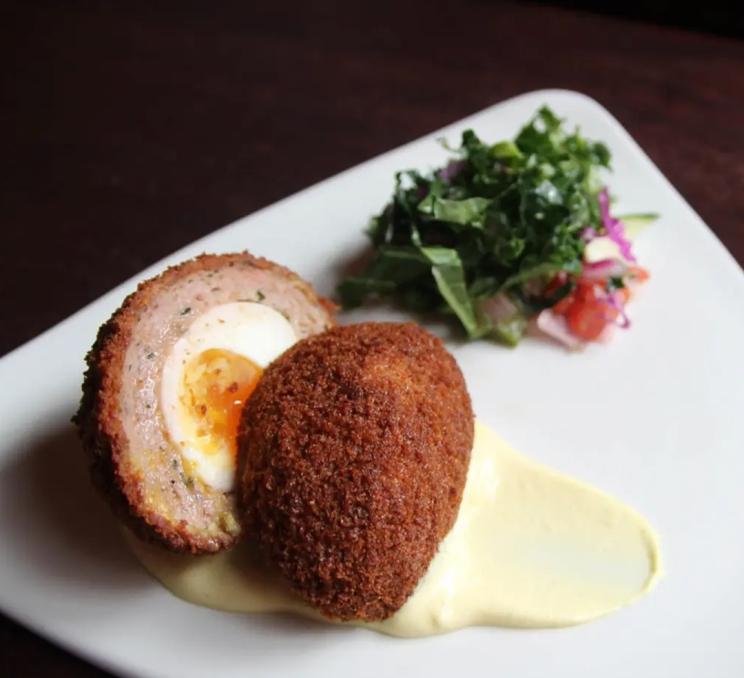 A Scotch Egg on a plate with a small assortment of greens at the Irish Times Pub in Victoria, BC