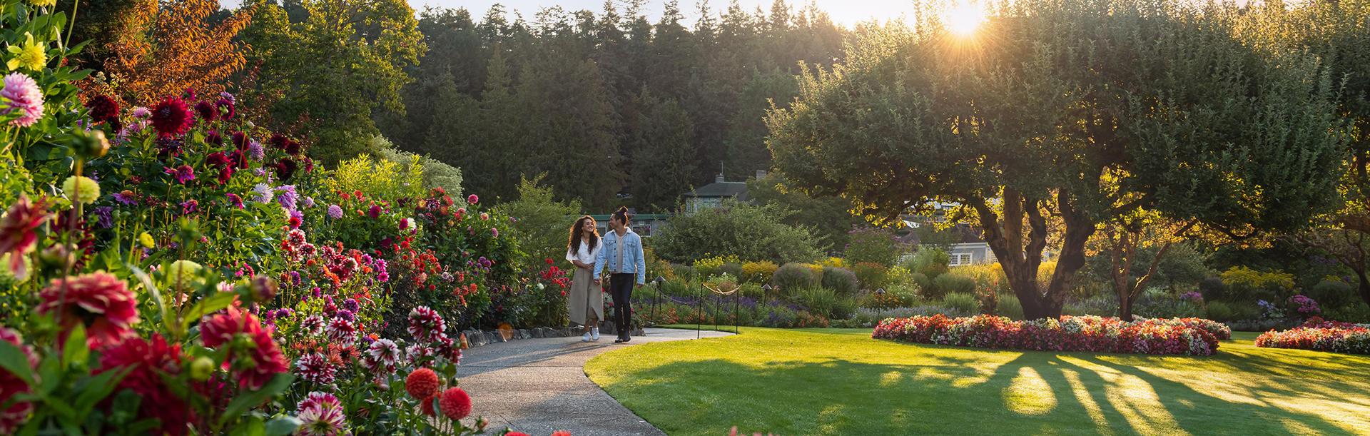 A young couple walk together along a flowered pathway at The Butchart Gardens, a National Historic Site of Canada display garden in Victoria, BC