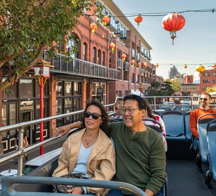 A couple take a ride on a hop on, hop off bus through Victoria, BC's Chinatown