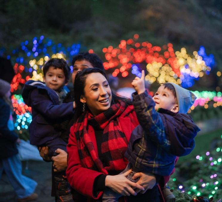 A young family walks through the Sunken Garden during The Butchart Gardens annual holiday light display, The Magic of Christmas, in Victoria, BC