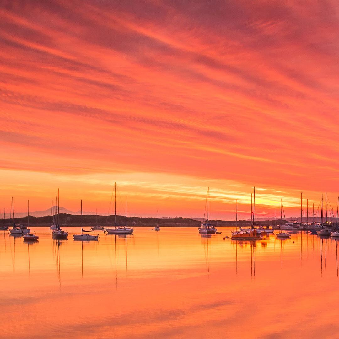 A sunrise over the Oak Bay Marina in Victoria, BC with the silhouette of Mount Baker on the horizon