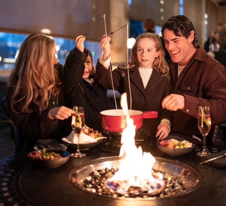 A family dines on fondue at a fire table on the Veranda at the Fairmont Empress in Victoria, BC