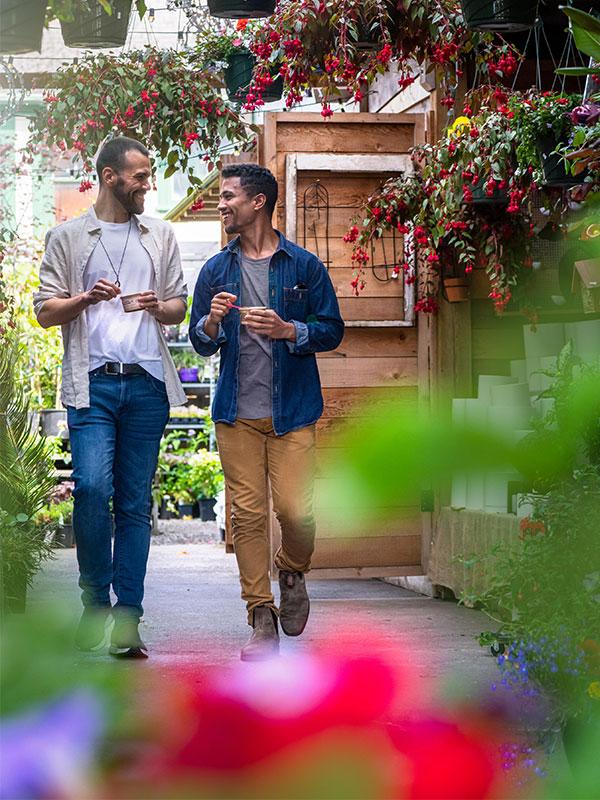 A couple eating ice cream walks through a flower shop in the Cook Street Village neighbourhood of Victoria, BC