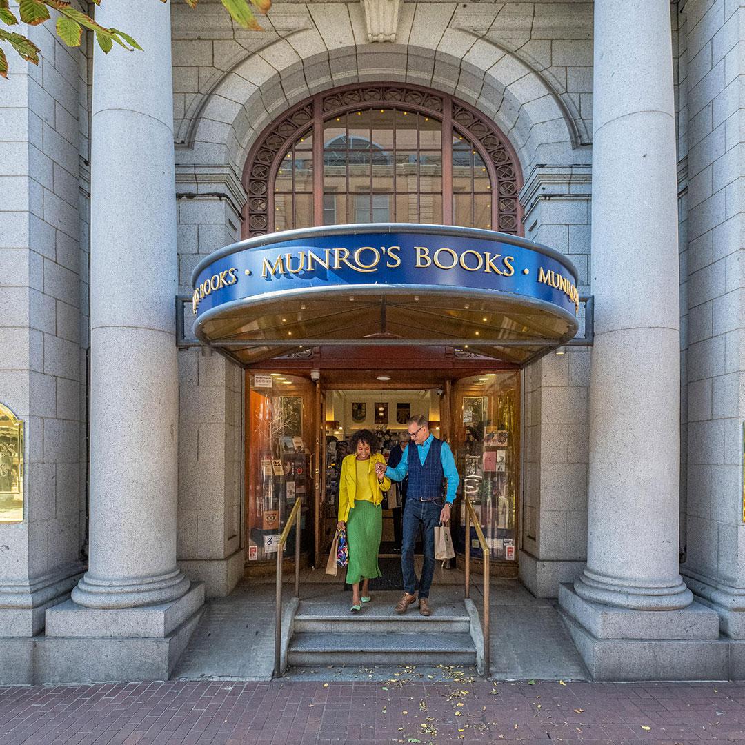 A couple walking out of Munro's Books on Government Street in Victoria, BC after shopping