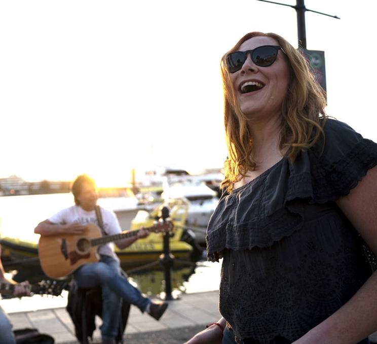 A woman dancing to buksers on the Lower Causeway of the Inner Harbour in Victoria, BC