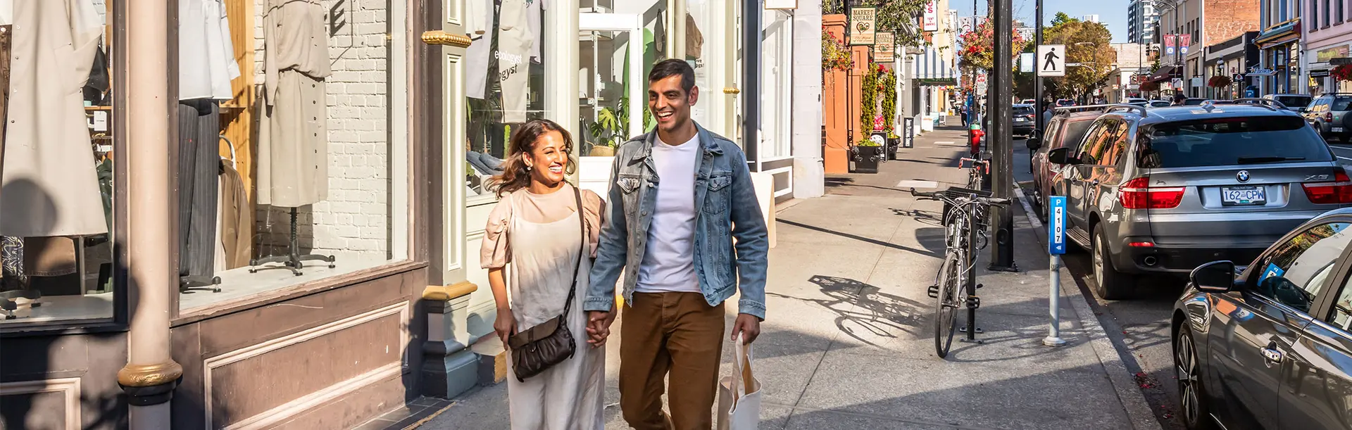A couple walking hand-in-hand down Lower Johnson Street while shopping in Victoria, BC