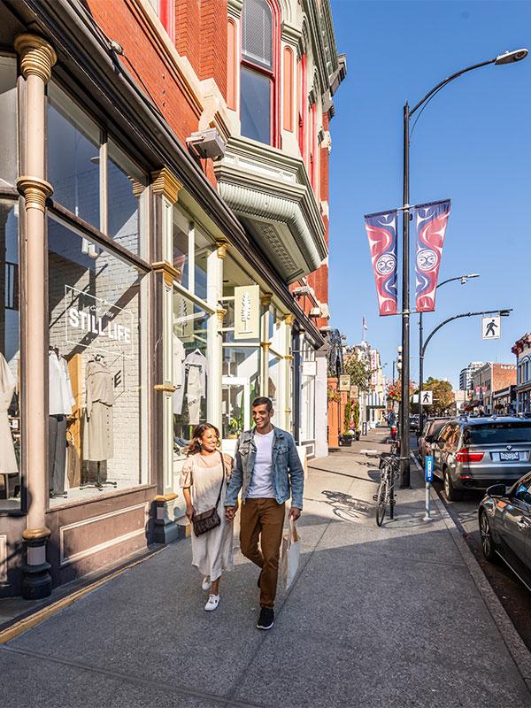 A couple walks hand-in-hand down Lower Johnson Street in downtown Victoria, BC