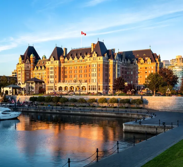 The Fairmont Empress hotel on Victoria, BC's Inner Harbour is illuminated by a sunrise