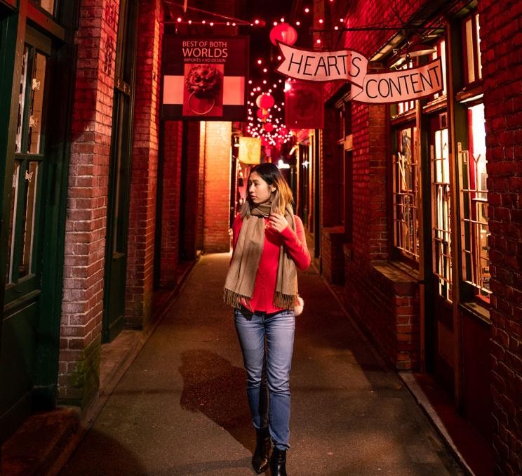 A woman in red walks through Fan Tan Alley at night in Victoria, BC's Chinatown