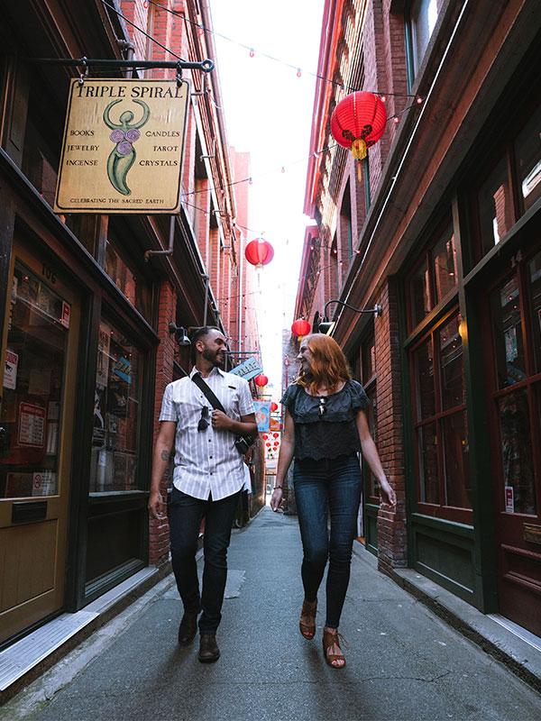 A couple walks through Fan Tan Alley, Canada's Narrowest Street, in Victoria, BC