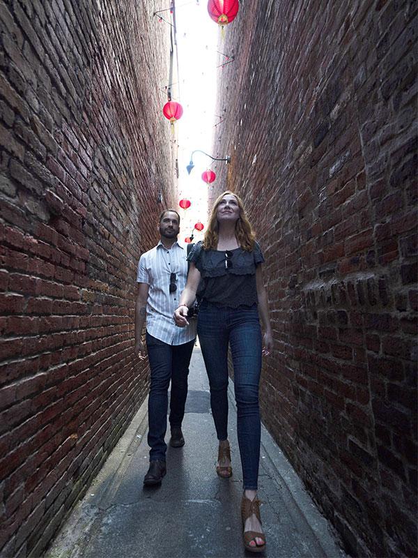 A couple walks through the entranceway of Fan Tan Alley in Victoria, BC's Chinatown